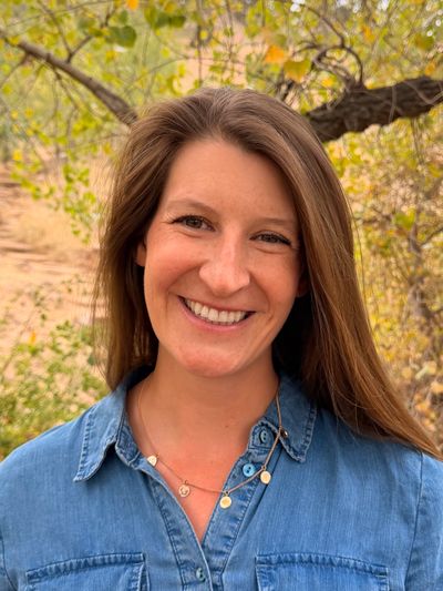 Allison Eckmann smiling outdoors, wearing a denim jacket over a green top.